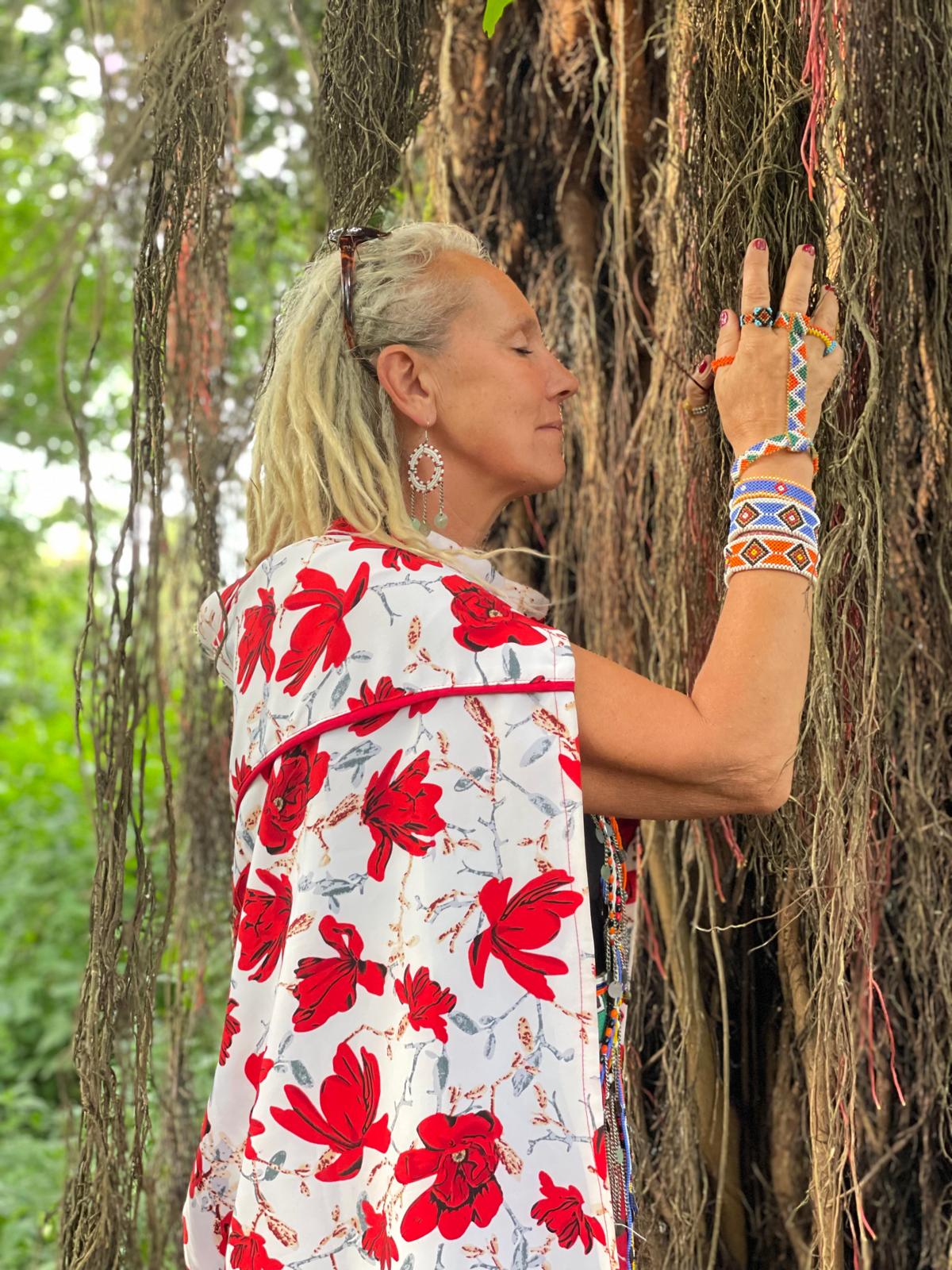 Voyageuse enlaçant un arbre millénaire dans la forêt sacrée Naimina Enkiyio, en terre maasaï — retraite initiatique Nenkaï